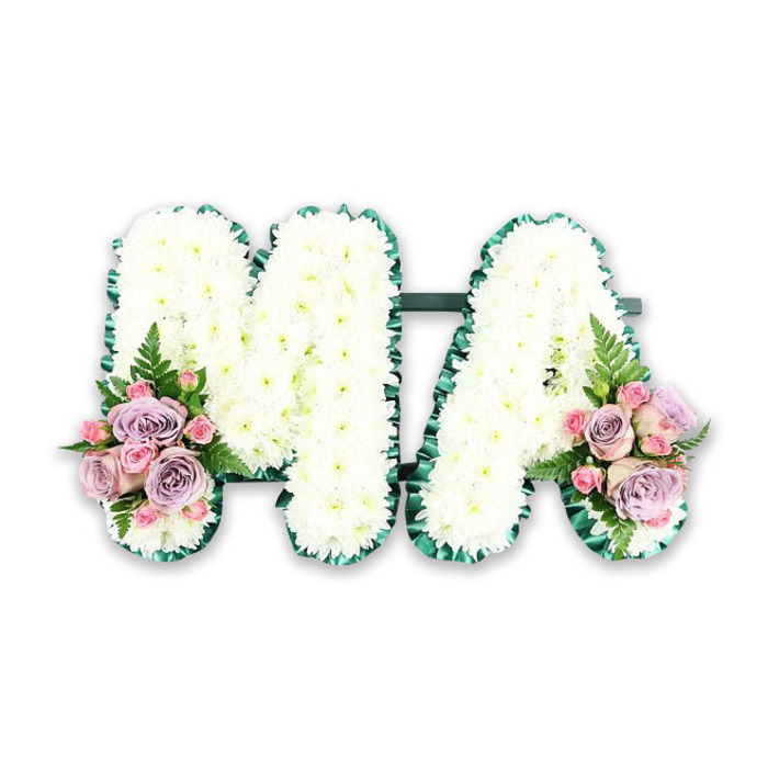 A personalised MA funeral letter tribute is captured here in a clear, studio-style photograph, radiating a sense of quiet dignity and deep affection. The two capital letters sit side by side, supported by a hidden frame that keeps them upright yet unseen, so all attention rests on the flowers themselves. Every inch of the 'M' and 'A' is covered with small white chrysanthemums, their petals arranged in overlapping layers that create a soft, almost cloud-like surface. The consistency of the white blooms gives an impression of purity and calm, ideal for families in Harold Wood seeking a gentle, respectful tribute to a loved mother or grandmother. Along the outer perimeter of each letter runs a rich green satin ribbon, meticulously ruffled and pinned into place. This emerald border frames the floral work like a carefully chosen mount around a treasured photograph, clearly defining each curve and angle. At the base of the letters, two complementary floral sprays add a romantic touch of colour. Here, blush-pink roses open in full, rounded heads, interspersed with smaller pink spray roses and stately lilac or lavender roses. The colour blend is soft and refined, not overpowering the white, but rather enhancing it with warmth and tenderness. Sprigs of fern and slim green foliage emerge from between the roses, bringing a touch of natural movement that evokes nearby green spaces and gardens around Harold Wood. The lighting is bright, evenly distributed, and neutral, ensuring no shadows distract from the intricate detailing. This MA design is the kind of bespoke funeral tribute that might be chosen by a close family, perhaps a child or grandchild, to stand beside the coffin or near the lectern, quietly saying thank you, Ma in flowers.