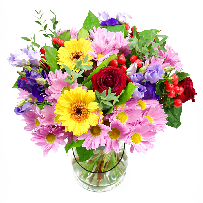 A lush, colourful bouquet fills a simple clear glass vase, the entire arrangement photographed against a bright white background that allows each bloom to sing. At the centre, sumptuous deep red roses unfold in velvety layers, their rich hue and classic form lending an air of timeless romance and sincerity, ideal for heartfelt messages in Harold Wood. Nearby, two sunny yellow gerbera daisies with dark brown-orange centres shine brightly, their broad, open faces bringing a happy, upbeat note that suggests celebrations, milestones, and cheerful gatherings on local streets like Gubbins Lane or around Harold Wood's quiet cul-de-sacs. Encircling these main flowers, generous clusters of soft pink daisies or chrysanthemums spread out, each flower made up of slender petals and a tiny yellow centre, creating a soft cushion of pastel colour that adds volume without overpowering. Interlaced throughout are slender stems of purple and lavender lisianthus, their bell-shaped blooms and ruffled edges contributing cool, sophisticated tones and a sense of gentle movement. Nestled between petals, bright red hypericum berries appear as glossy, round accents, bringing playful texture and small pops of colour that keep the eye moving across the arrangement. A blend of greenery-broad, deep green leaves alongside finer, lighter foliage-wraps the bouquet in a natural frame, conjuring the feeling of a hand-gathered armful of flowers from a local Harold Wood garden. The transparent vase reveals neatly trimmed stems resting in clear water, highlighting the professional care taken in crafting the piece, as you would expect from Flowers Harold Wood. Altogether, the bouquet radiates warmth, joy, and thoughtful artistry, making it a versatile centrepiece for birthdays, congratulations, or simply brightening a favourite room with a sense of fresh, local beauty.