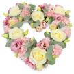 A tender, heart-shaped floral wreath fills the frame, its romantic pastels enhanced by a flawless white background. The shape of the heart is soft but unmistakable, built from a tightly packed arrangement of blossoms that form a rich, textured surface. Creamy ivory and light yellow roses are evenly spaced across the design, their full, layered petals giving the eye steady points to rest upon as it follows the curve of the heart. Nestled around them, clusters of pale pink carnations add a plush, almost cloud-like quality, each frilled petal contributing to the sense of gentle abundance. Deeper pink and mauve lisianthus blooms punctuate the softer tones, their more relaxed, trumpet-shaped flowers and slightly rippled petals adding movement and emotional depth, like quiet echoes of cherished memories. Woven through the blooms are slender stems of eucalyptus, with rounded, silvery-green leaves that bring a restful, cool contrast and subtly sketch the outline of the heart. Fresh yellow-green buds appear here and there, symbolising new beginnings even in a time of grief. The overall impression is serene, loving, and deeply respectful, a piece that seems to speak on behalf of family and friends when words are difficult to find. In Harold Wood, an arrangement like this could be prepared by Flowers Harold Wood for same-day delivery to a local chapel, crematorium, or family home, where it would stand as a focal point during a funeral or memorial. Its gentle fragrance and soft colours offer comfort and a sense of unity, reflecting the enduring love that surrounds a life being honoured.