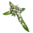 A solemn yet gently radiant floral cross photographed against a clean white backdrop at a slight overhead angle so the defined arms and central meeting point are clearly visible. Broad, glossy tropical leaves - reminiscent of Ti leaves - form the strong verdant structure, their rich green sheen and pronounced veins creating a protective, sculpted base that reads almost like sheltering wings. At the heart of the cross and tracing each arm is a lush cascade of pale blooms: creamy-white lisianthus with softly ruffled petals and unopened buds, intermingled with small, bright white daisy-like chrysanthemums that add a crisp, comforting texture. Scattered among them are sprays of delicate, powdery lavender or light-purple accent flowers, likely limonium or tiny asters, introducing a subtle cool contrast that lifts the composition without breaking its calm. Finer green filler foliage peeks through the clusters, lending depth and an organic, garden-fresh feel. The even, soft lighting warms the whites and highlights the leaf gloss, suggesting a tranquil morning light that would be fitting for a funeral chapel, church service, or graveside tribute. The arrangement reads as a classic sympathy piece: restrained, dignified and thoughtfully balanced to convey reverence and consolation. Tactile contrasts - the waxy smooth leaves against the feathery softness of the lisianthus and the tiny, textured centres of the chrysanthemums - are easy to imagine by touch, and the overall scent would be quietly green and faintly floral. This cross is a visual expression of peaceful remembrance, equally at place in a Harold Wood chapel near the station or as a respectful memorial on its own against a plain background.