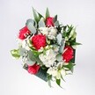 A hand-tied bouquet brimming with red roses, pink-red carnations, and soft white daisies is captured in gentle daylight, as if just set down on a kitchen table in Harold Wood. The velvety roses form a confident heart to the arrangement, their rich crimson petals spiralling tightly, while the carnations around them are slightly ruffled, almost feathery, adding movement and texture. Small daisy-style chrysanthemums with snow-white petals and sunny yellow centres bring a light, joyful brightness, echoing the feeling of a fresh morning walk through Harold Court Woods. Between the blooms, tiny clouds of gypsophila float delicately, their pinpoint blossoms softening the stronger reds and creating a sense of airiness. Eucalyptus stems curve outward, their rounded, silvery-green leaves giving a modern, herbal freshness, while deeper tropical foliage in glossy forest greens frames the composition and adds depth. The bouquet feels carefully balanced and thoughtfully composed, never stiff, as though an expert local florist has trusted their eye and instinct rather than a rigid formula. You can almost sense the faint mingling of rose perfume and clean eucalyptus as if the flowers have just arrived for a birthday breakfast, a welcome-home surprise, or a quiet celebration of good news. The stems are bound neatly at the base, suggesting it could be placed into a favourite vase the moment it's delivered across Harold Wood and nearby streets, ready to brighten a hallway console, living room sideboard, or office desk. Overall, the image conveys a mood of gentle excitement and affectionate intention, a bouquet made to mark life's happy, everyday milestones with colour, freshness, and sincere warmth.